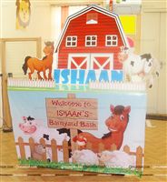 Cake table setup for small house parties with a 3 feet red barn cutout along with relatively sized cutouts of a horse and cow. The table is fenced with wood pegs to represent the farm. 