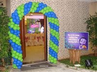 Krishna theme birthday Entrance decor with balloon arch made of green and blue balloons and a welcome poster personalised with the baby name