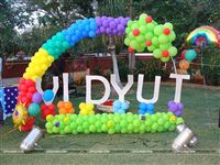 Baby name cutout with a rainbow balloon arch for a 1st birthday party