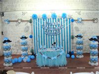 Little Man Stage Setup includes Blue Pompoms, Blue White & Silver metallic balloon pillars, Streamers and a Happy Birthday Bunting for the backdrop, Blue Tutu table cover, Hats and Center pieces