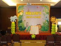 Stage setup for a Jungle Birthday party with a 8 feet backdrop and two balloon pillars on either side along with an Elephant and Lion cutout. 